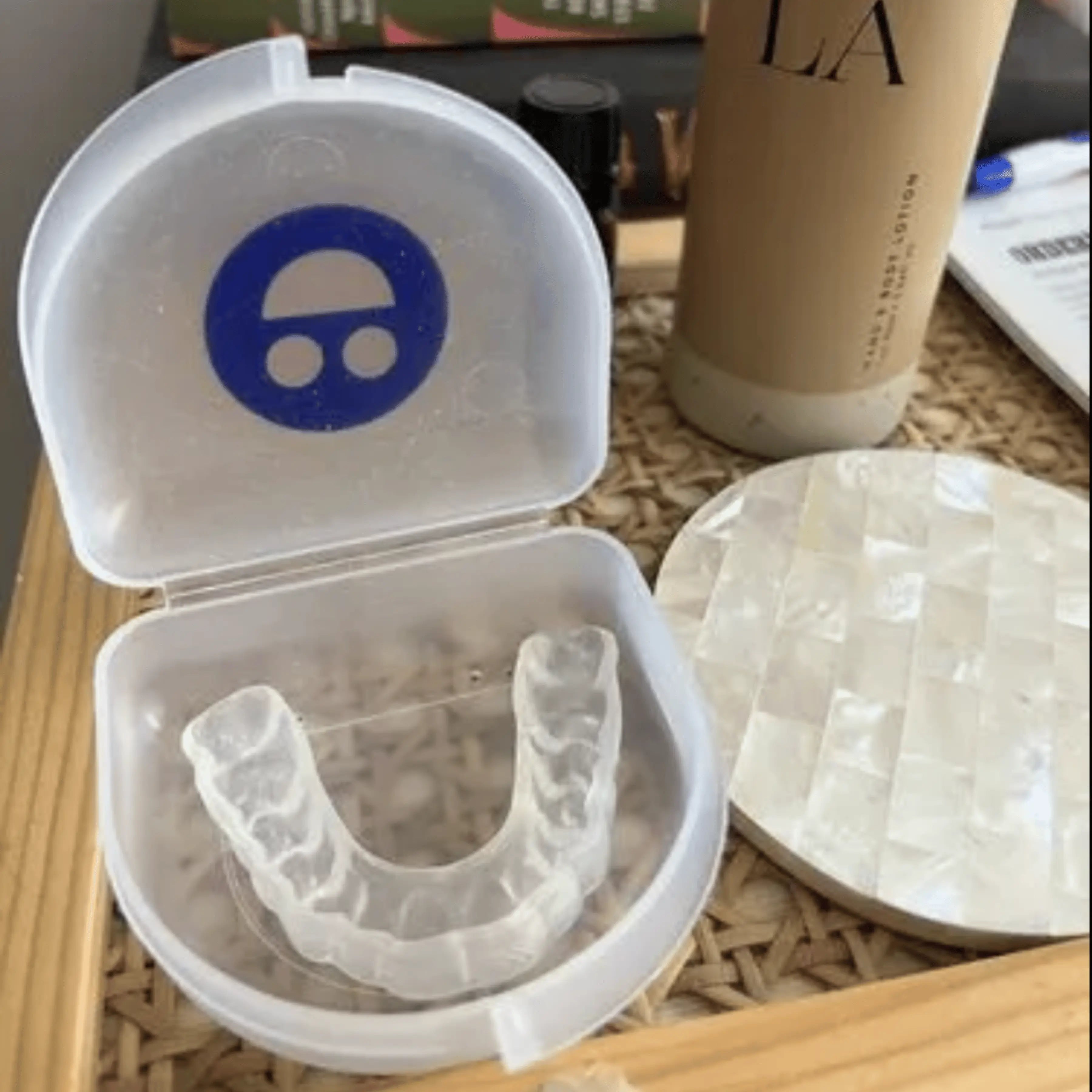 Clear mouthguard in a white case on a wooden surface with a blurred background